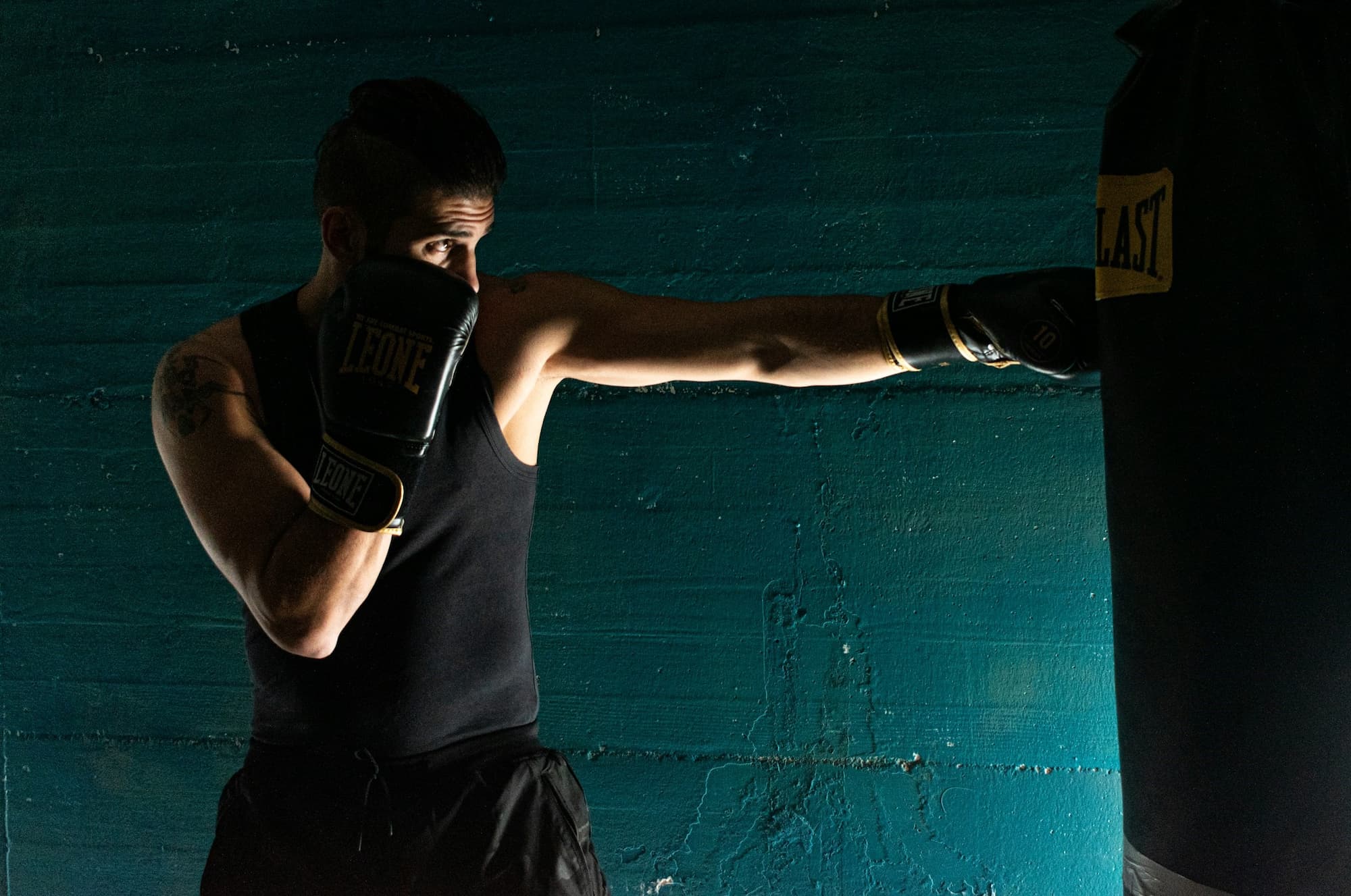 Man in black tank top punching a boxing bag